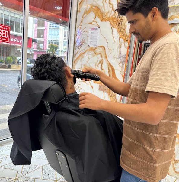 Barber giving a customer a haircut at Newaj Barber Shop Setia Alam
